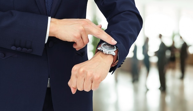 Zakenman met vinger wijzen op zijn horloge in zijn hand. aan de rechterkant