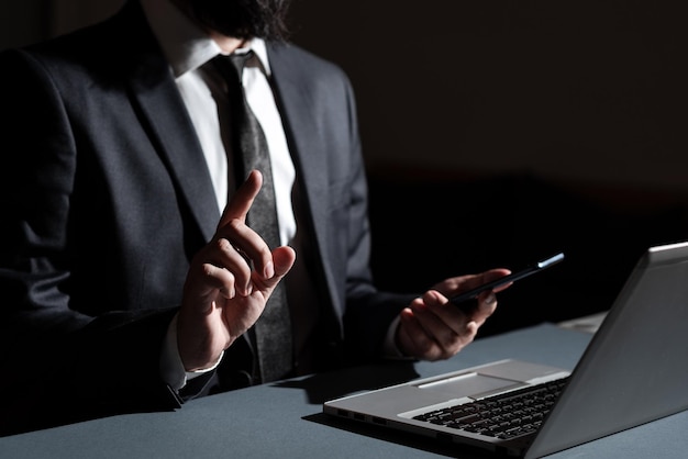 Zakenman mobiele telefoon in de hand te houden en met één vinger te wijzen op belangrijk bericht op bureau met lap top Man met mobiele telefoon en nieuwe ideeën met één hand presenteren