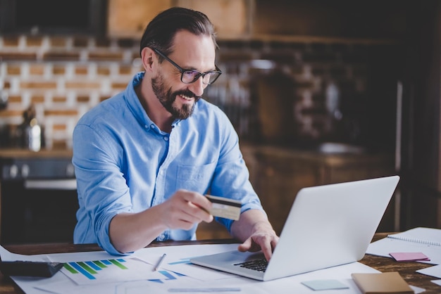 Zakenman online winkelen met creditcard en laptop thuis gebruiken