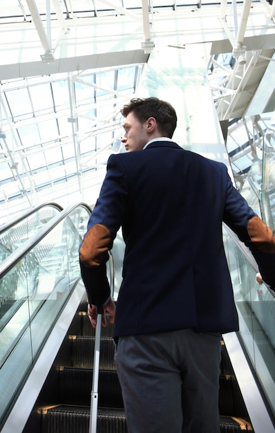 Zakenman op de luchthaven die de roltrap afgaat.