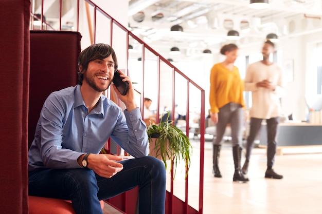 Zakenman op telefoon zittend bij de trap In moderne open kantoor