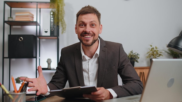 Zakenman op zijn kantoor, papieren aan het analyseren, geschokt door de plotselinge overwinning. Goed nieuws.