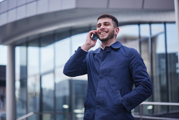 Zakenman praten aan de telefoon op straat voor het kantoor