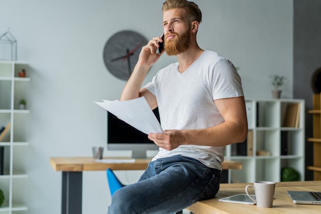 Zakenman praten over mobiel zittend op kantoor.