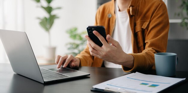 Zakenman s handen typen op smartphone tablet en laptop toetsenbord computer typen online in kantoor