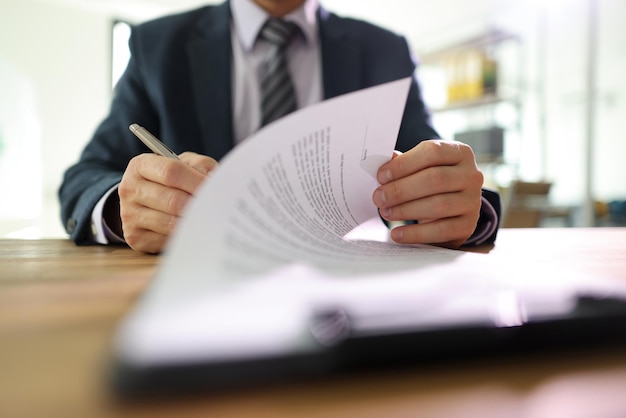 Zakenman slaat pagina van contractondertekening om met pen na lezing van man in klassiek pak