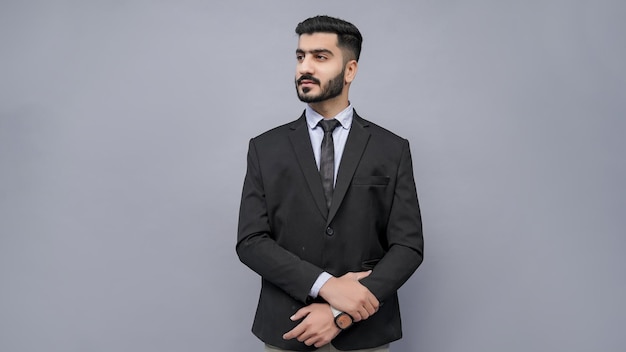 zakenman staande met gekruiste hand naar links kijkend in zwart pak Indisch Pakistaans model