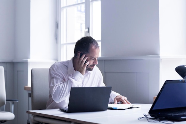 Zakenman telefoneren met smartphone aan zijn bureau