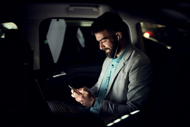 Zakenman typen op mobiele telefoon in de auto.