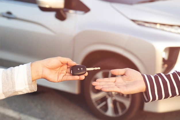 Zakenman uitwisseling overhandigen de autosleutels voor aan een jonge vrouw.