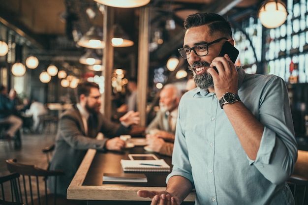 Zakenman van middelbare leeftijd met behulp van telefoon in de pub