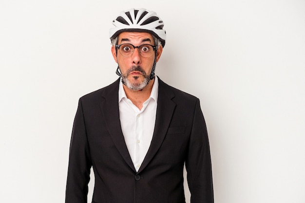 Zakenman van middelbare leeftijd met een fietshelm geïsoleerd op blauwe achtergrond haalt zijn schouders op en verwarde ogen.