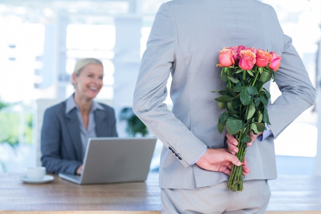 Zakenman verbergende bloemen achter rug voor collega