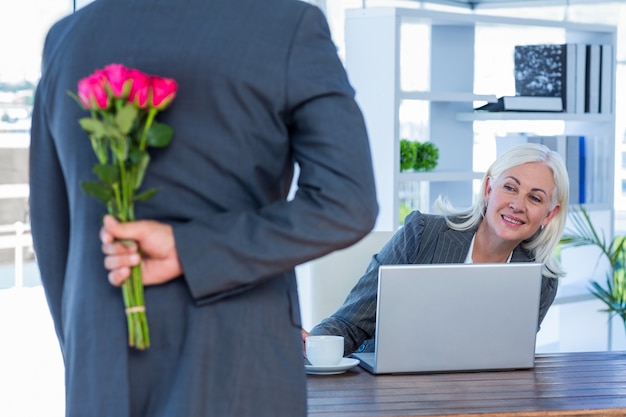 Zakenman verbergende bloemen achter rug voor collega