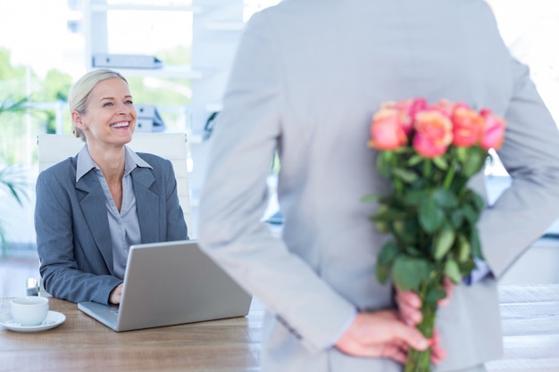 Zakenman verbergende bloemen achter rug voor collega