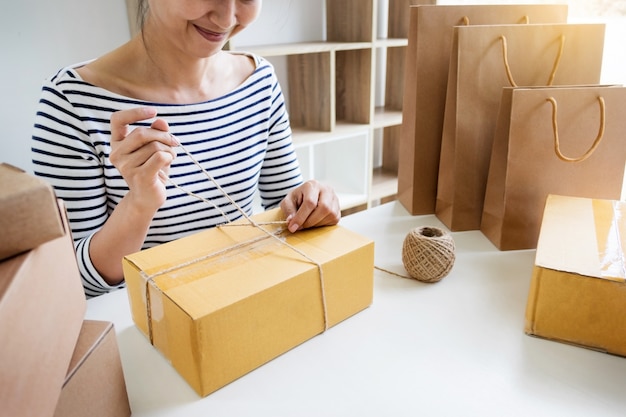 Zakenman vrouw die online winkelen gaat werken Voorbereiding van het productverpakkingsproces in haar huis, jong ondernemersconcept.