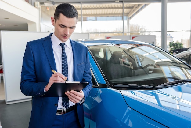 Zakenman vult documenten op auto in bij autodealer