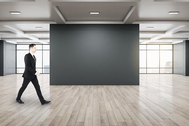 Zakenman wandelen in galerij interieur met lege zwarte wal