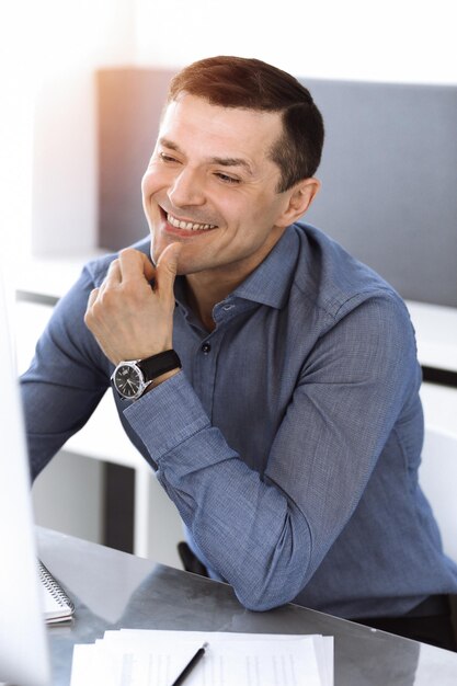 Zakenman werken met computer in moderne zonnige kantoor. Headshot van mannelijke ondernemer of bedrijfsleider op de werkplek. Bedrijfsconcept.