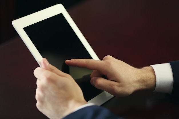 Zakenman werken met tablet aan houten tafel close-up