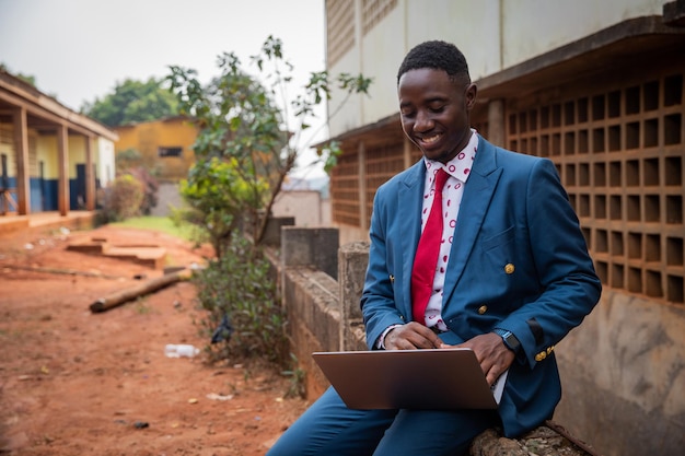 Zakenman werkt met zijn laptop, hij zit en staat buiten de succesvolle Afrikaanse ondernemer