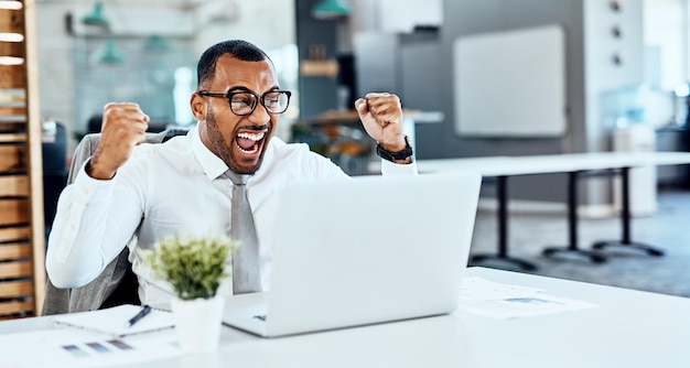 Zakenman winnaar en ja op computer succes nieuws of bonus in viering proost en wauw op kantoor Opgewonden vuist en winnende werknemer of persoon vieren op laptop promotie verkoop of resultaten