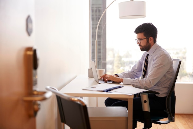 Zakenman zit aan bureau werkt op laptop in modern kantoor