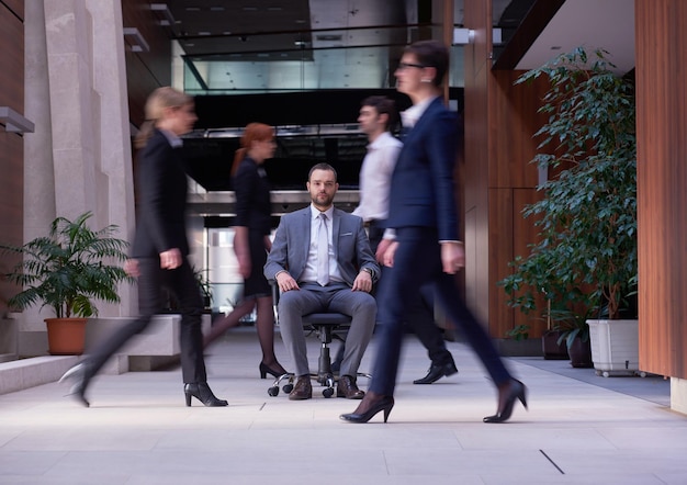 zakenman zittend in een bureaustoel, mensengroep langskomen: concept van tijd, haast, organisatie