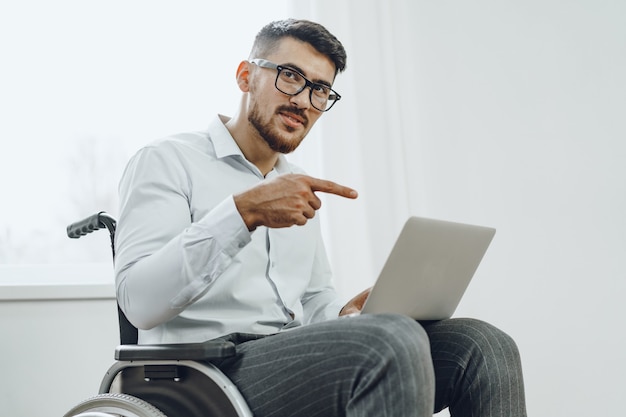 Zakenman zittend in een rolstoel en met behulp van laptop