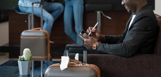 Zakenman zittend op de bank en met behulp van digitale tablet in de luchthavenlounge wachten op de vlucht