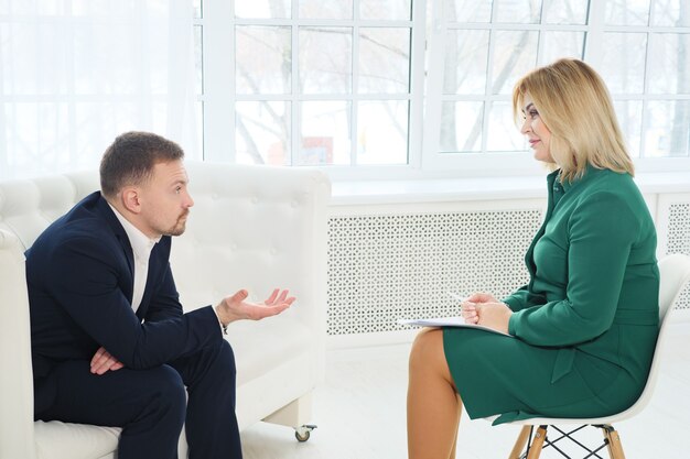 Zakenman zittend op de bank praten met vrouwelijke psycholoog.