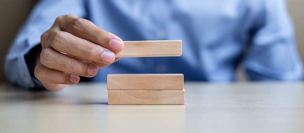 Zakenmanhand die houten bouwstenen op lijst houden