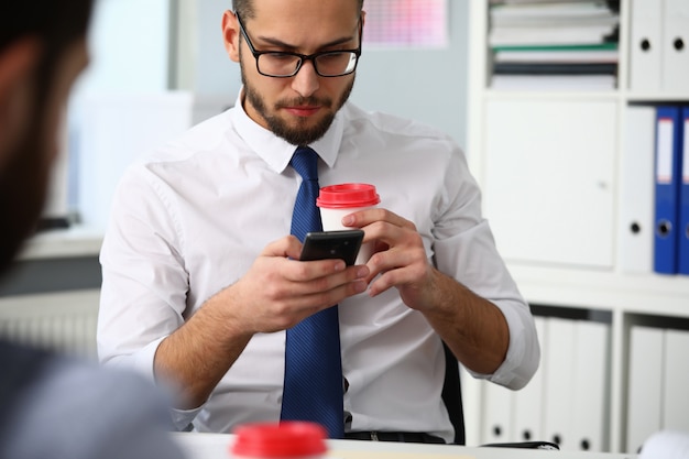 Zakenmanholding in wapenskop van koffie en celtelefoon