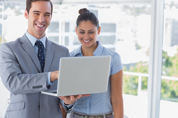 Zakenmanpartners die laptop en het lachen bekijken