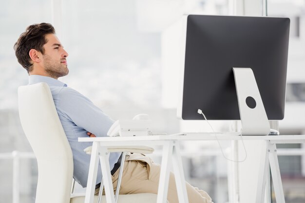 Zakenmanzitting met wapens in het bureau worden gekruist dat