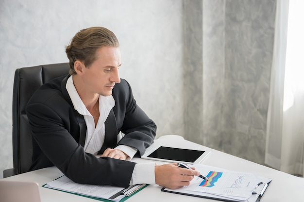 Zakenmanzitting op het zijn werk voor laptop computer terwijl het doen van sommige bedrijfsadministratie