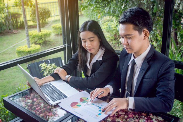 Foto zakenmensen bespreken grafieken terwijl ze een laptop op tafel gebruiken