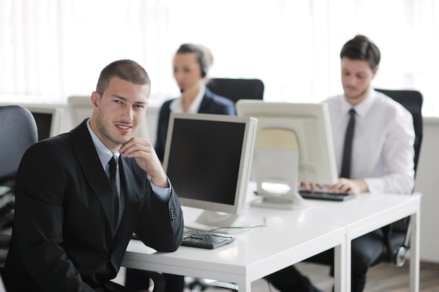 zakenmensengroep met koptelefoon die ondersteuning geeft in het helpdeskkantoor aan klanten, manager die instructies voor training en opleiding geeft