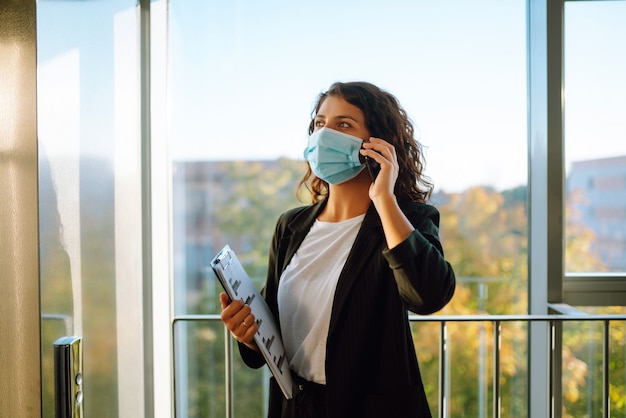 Zakenvrouw communiceren via mobiele telefoon terwijl het dragen van gezichtsmasker.