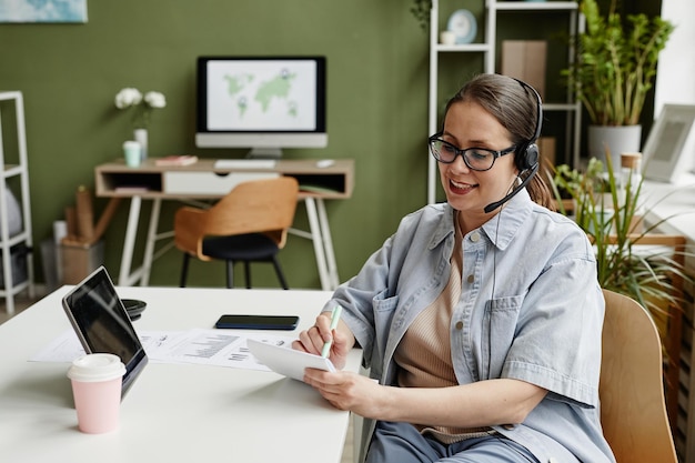 Zakenvrouw die aantekeningen maakt tijdens online gesprek