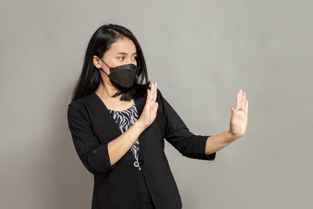 Zakenvrouw die een zwart masker draagt met een handgebaar wegblijven