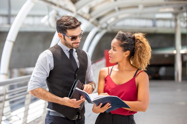 Zakenvrouw die met een collega praat terwijl ze op de voetgangersbrug staat