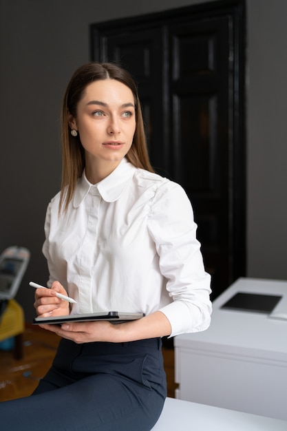 Zakenvrouw die met tablet werkt in een modern kantoor met een wit overhemd, een zwarte broek