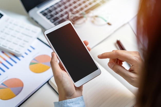 Zakenvrouw die mobiele telefoon gebruikt en aan het bureau werkt met marketinggrafiekstatistiekenanalyse