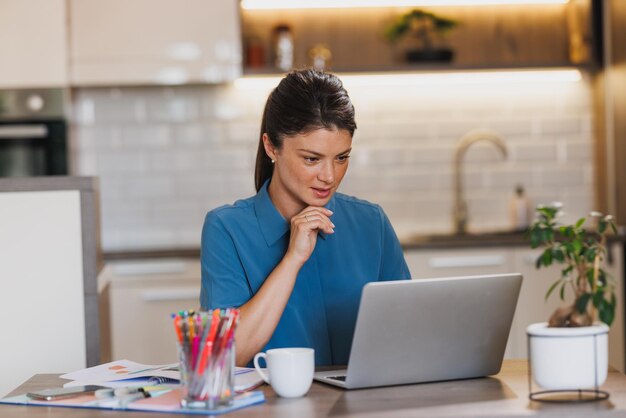 Zakenvrouw die op een laptop werkt vanuit haar kantoor.