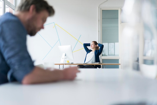 Zakenvrouw die op kantoor werkt met een collega die op de voorgrond zit