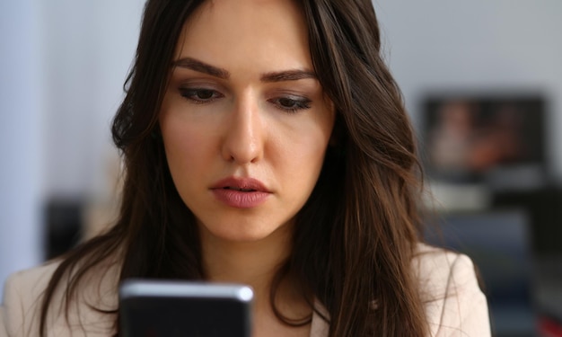 Zakenvrouw die smartphone gebruikt bij het lezen van sms-berichten op kantoor