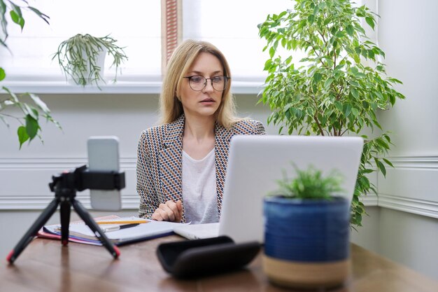 Zakenvrouw die thuis online werkt met laptop en smartphone