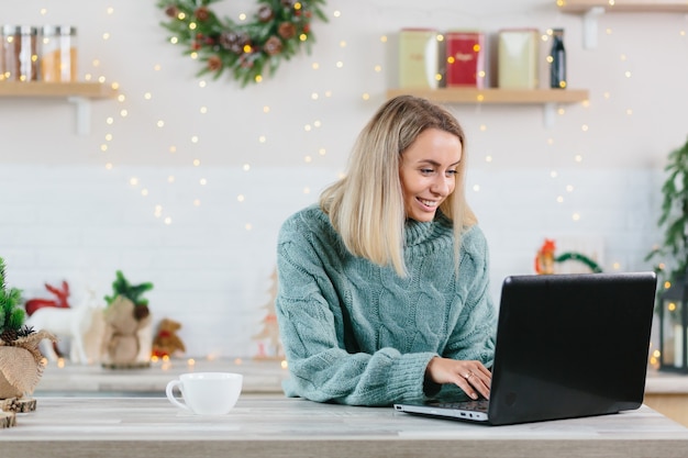 Zakenvrouw die thuis op laptop werkt tijdens Kerstmis en Nieuwjaar, gelukkig en succesvol voltooit een groot project