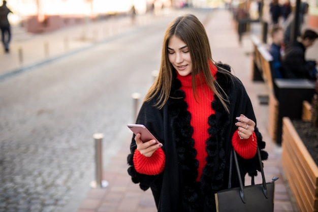 Zakenvrouw gebruikt smartphone op straat tijdens het lopen